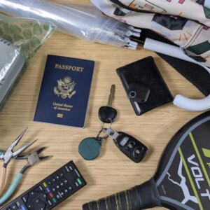 bluetooth trackers and various trackable items on bamboo desk including a passport, car keys, and umbrella
