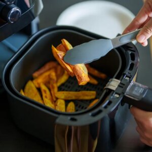 a person using tongs to lift food out of an air fryer
