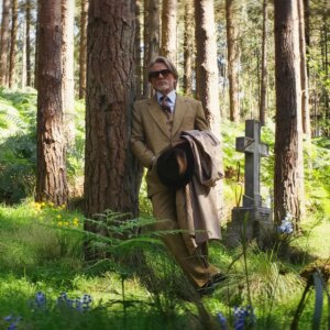 man stands against a tree in an old cemetery