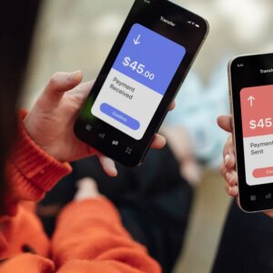 Two people hold phones sending money between apps.