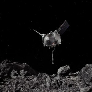 A spacecraft hangs floats just feet above the rocky surface of an asteroid