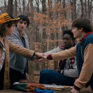 4 teen boys huddle together in the woods
