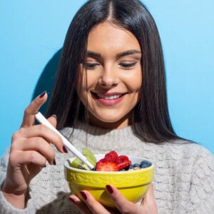 Woman easting bowl with fruits