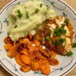 chicken, carrots and mashed potatoes in a shallow bowl on a brown table