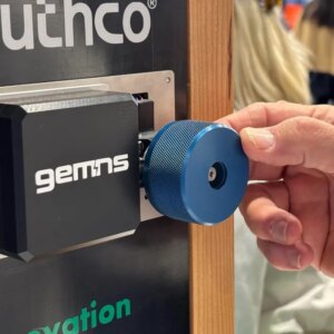 A hand turns a door knob on a demo at a trade show booth.
