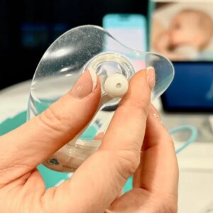 A woman in blue scrubs holding a silicone nipple shield