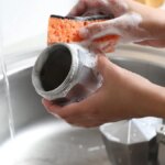 person cleaning moka pot with soap