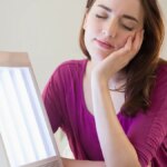 Woman using light therapy with a sun lamp to manage seasonal affective disorder